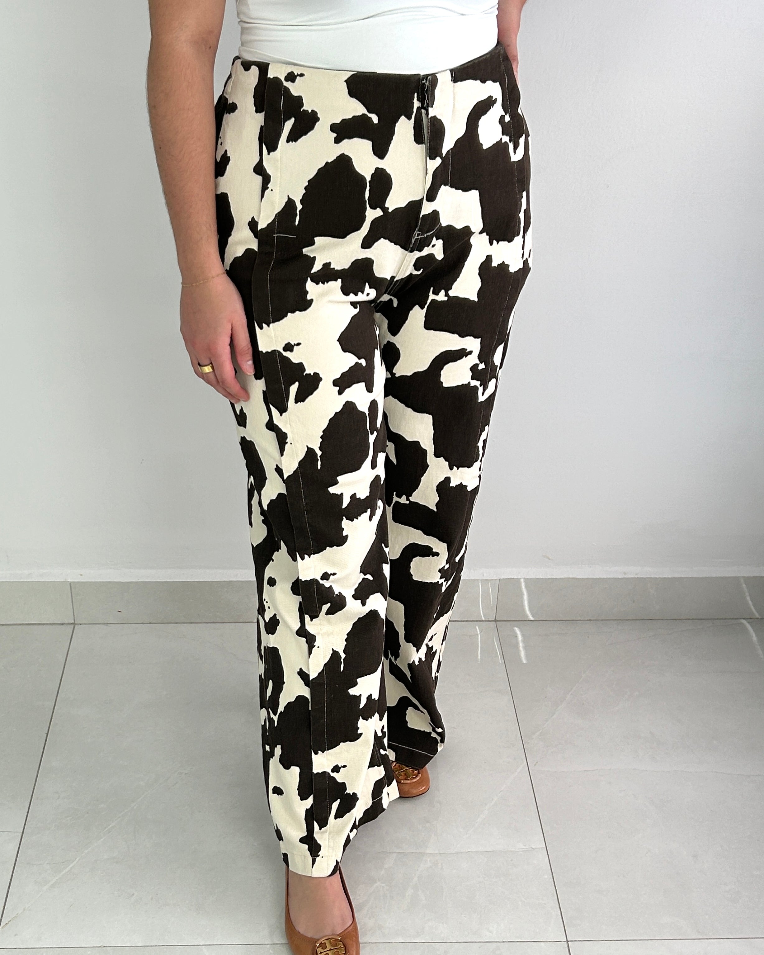 Person wearing a black and white cow print skirt on a plain background