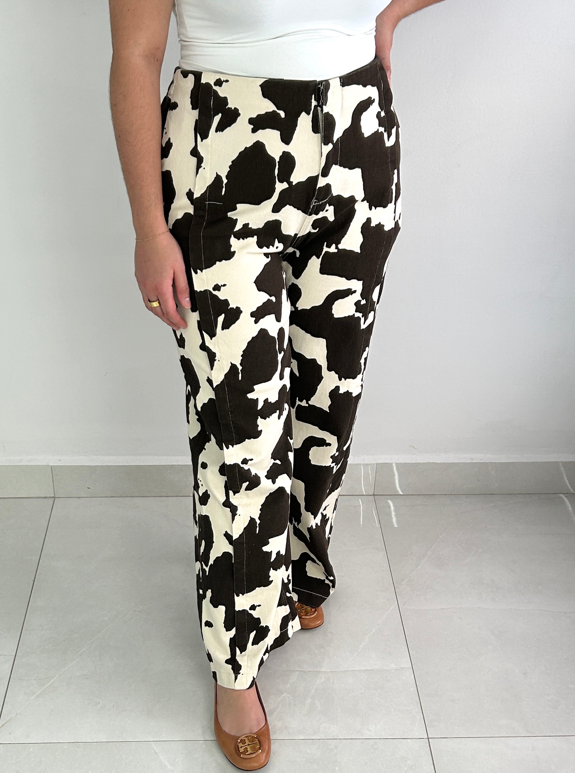 Person wearing a black and white cow print skirt on a plain background