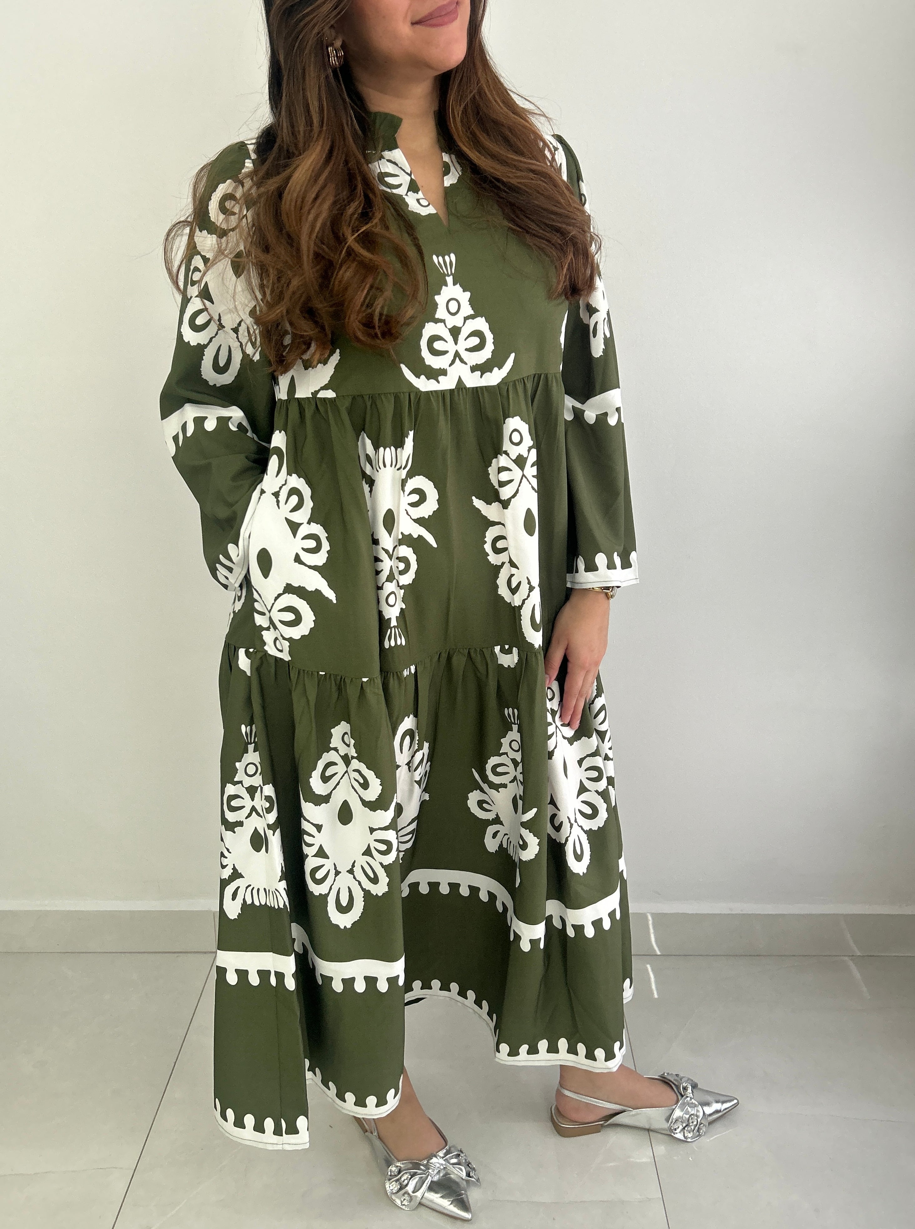Woman wearing a green dress with white patterns against a plain background