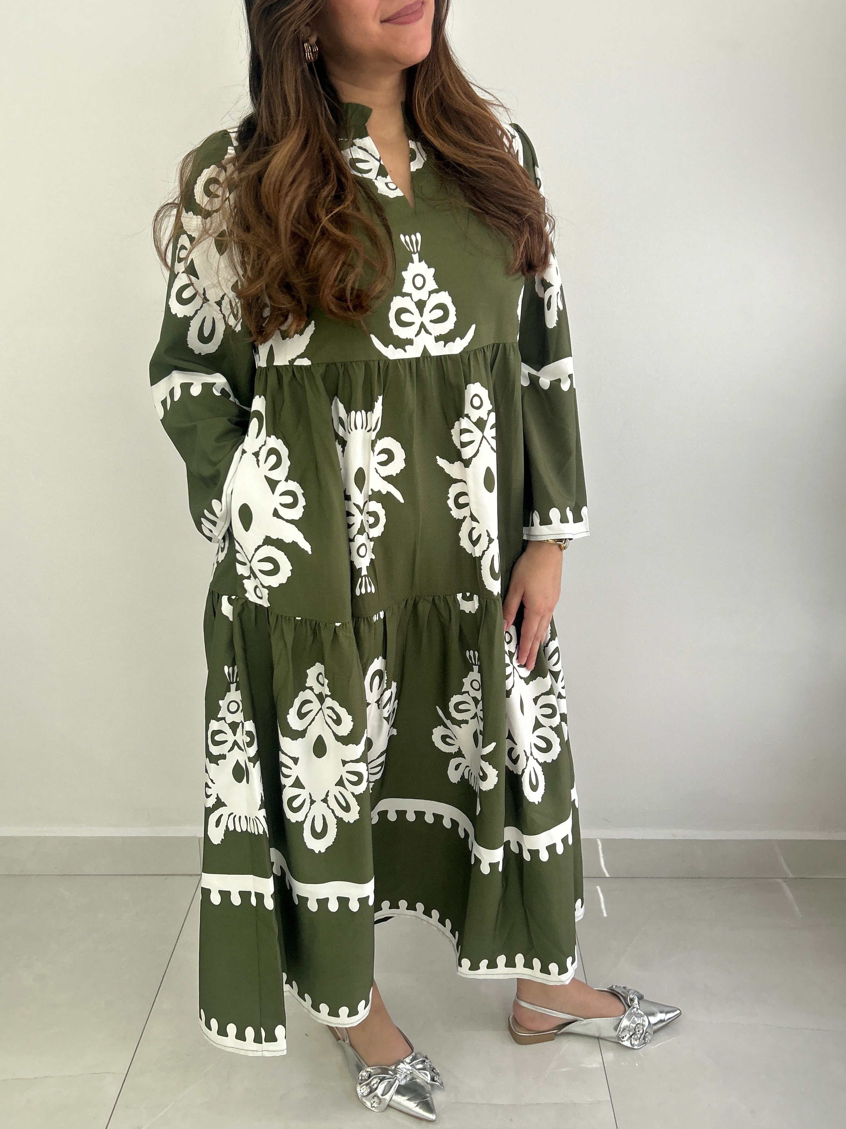 Woman wearing a green dress with white patterns against a plain background