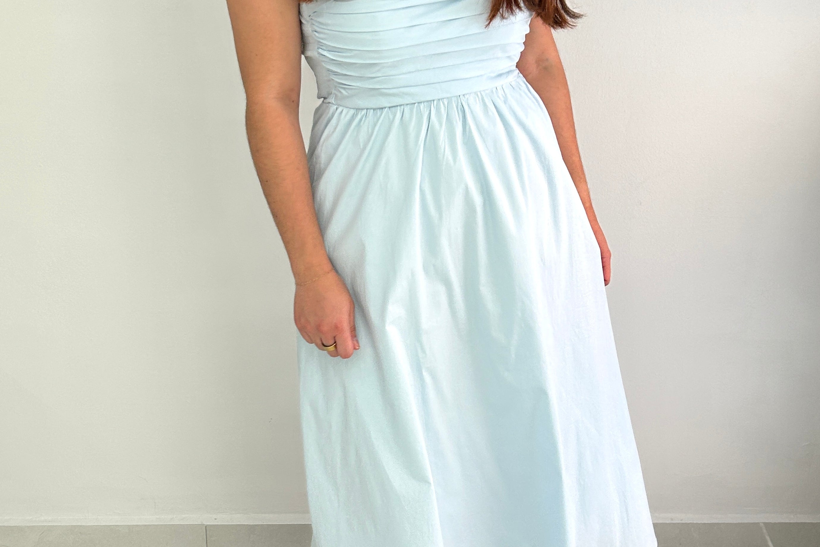 Woman wearing a light blue strapless dress against a plain background