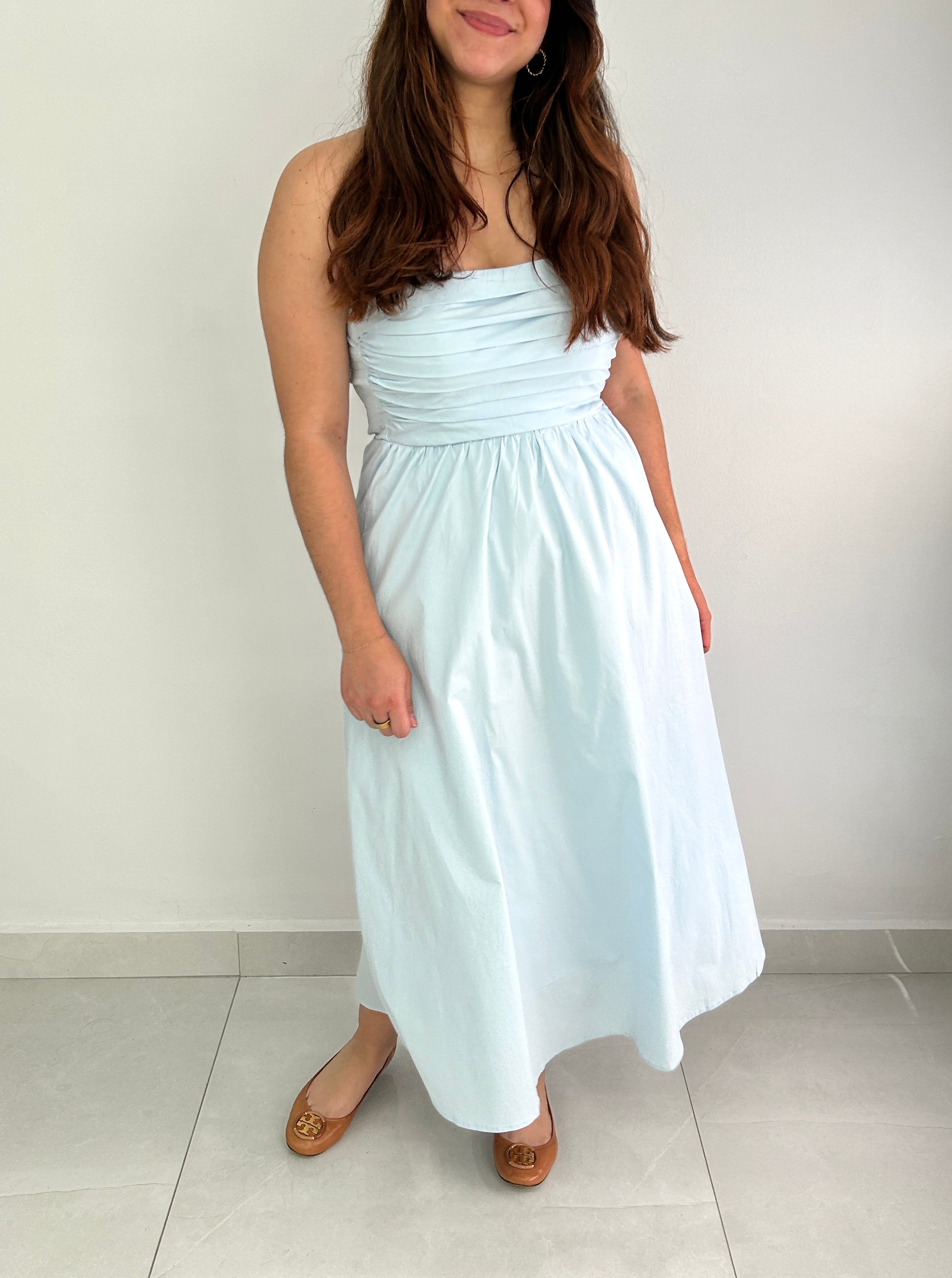 Woman wearing a light blue strapless dress against a plain background