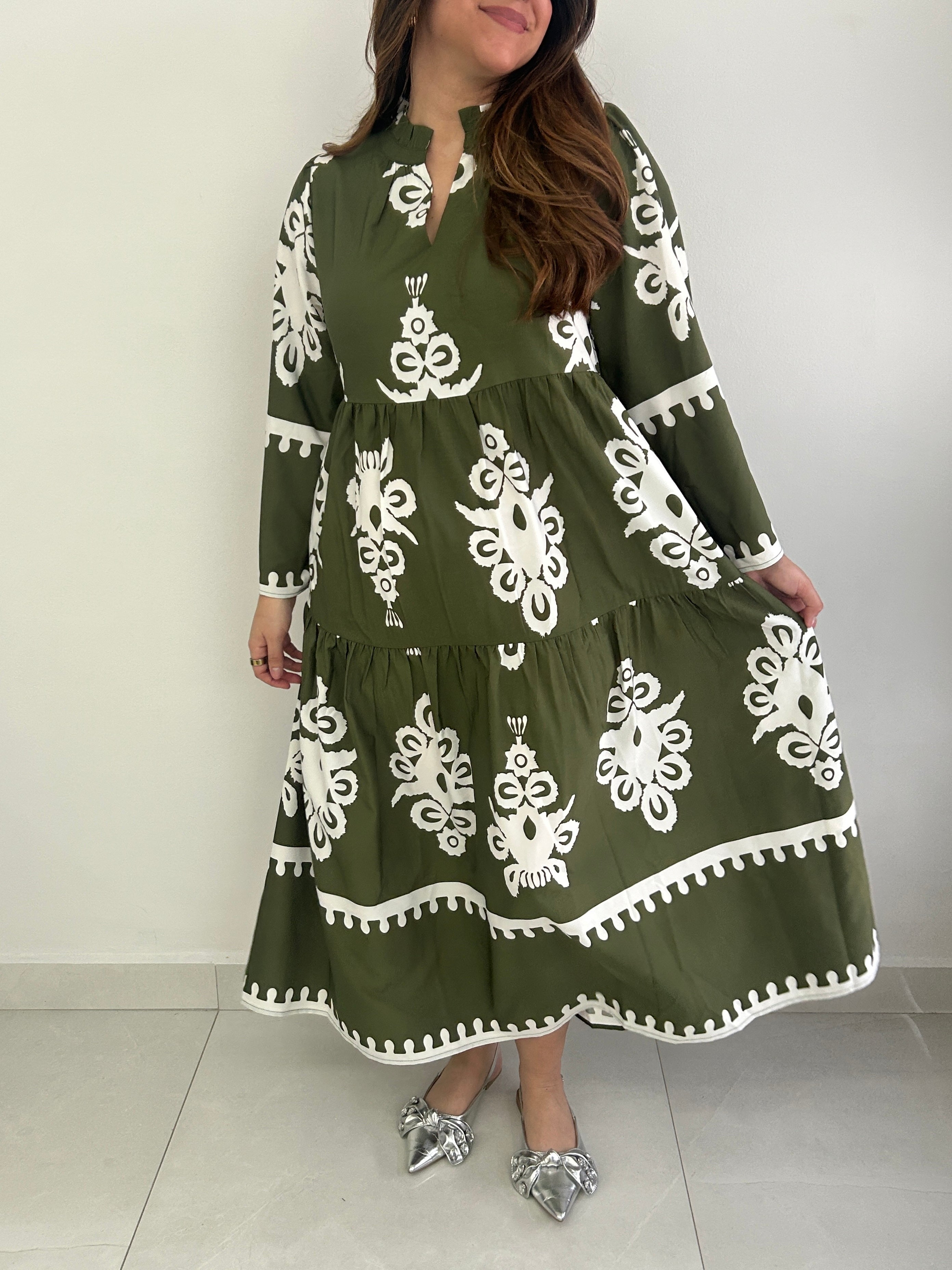 Woman wearing a green dress with white patterns on a white background