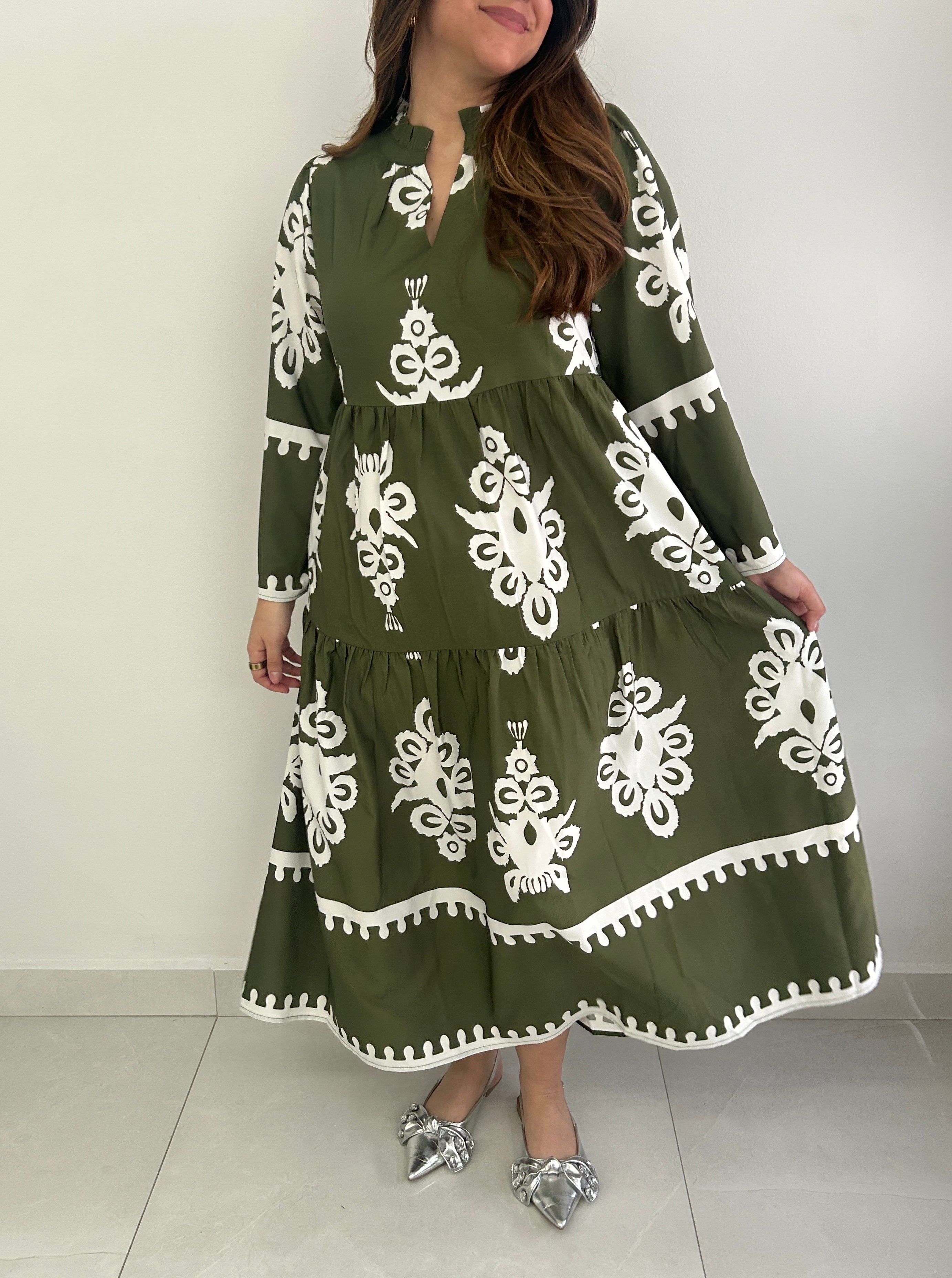 Woman wearing a green dress with white patterns on a white background