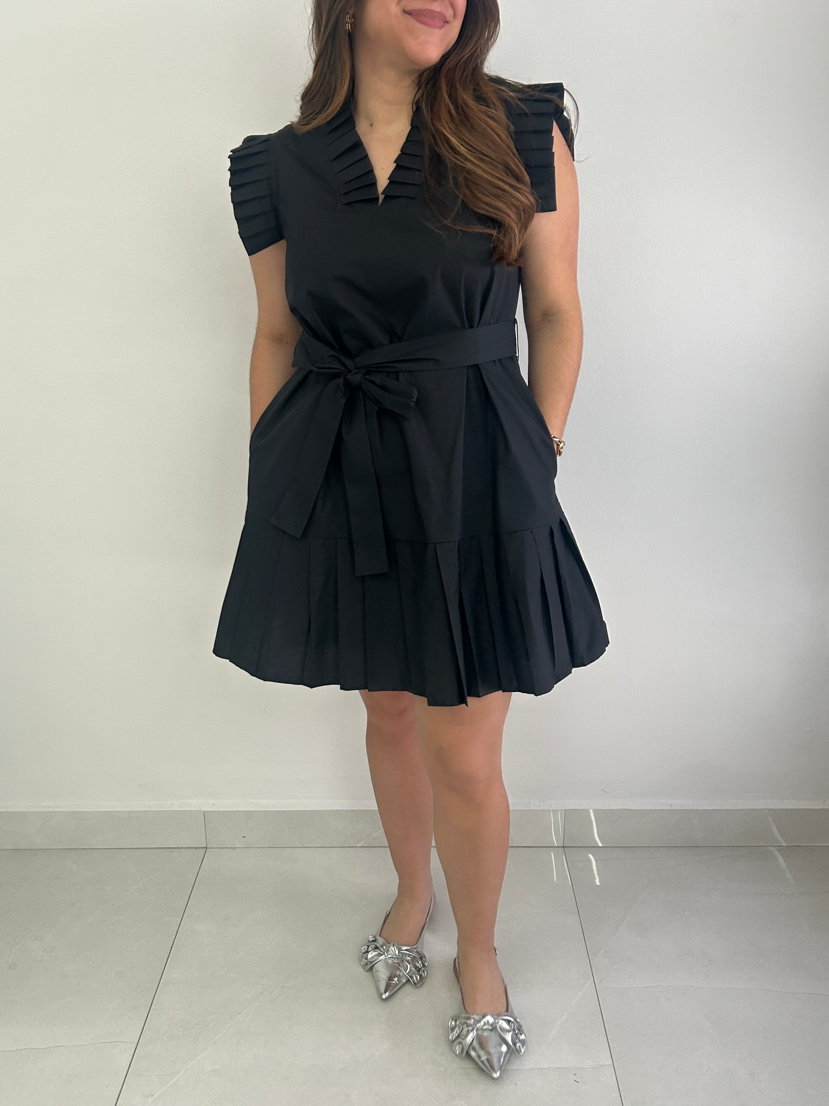 Woman wearing a black dress with a belt against a white background