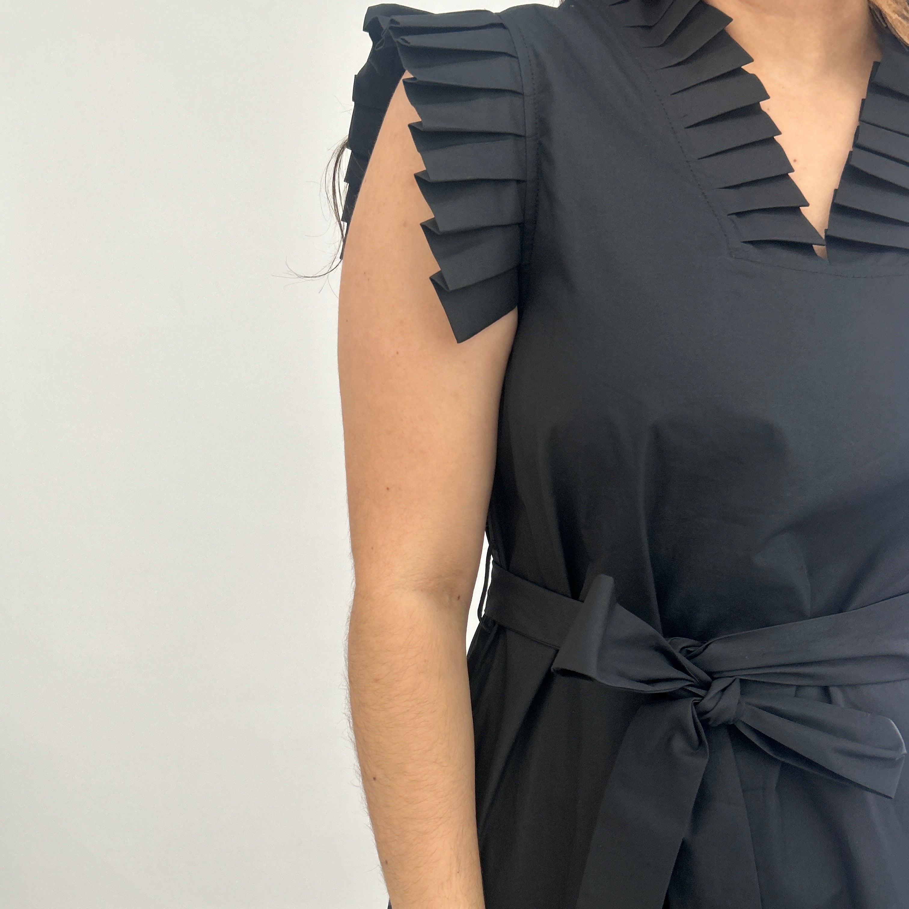 Black pleated dress with a tie detail on a white background