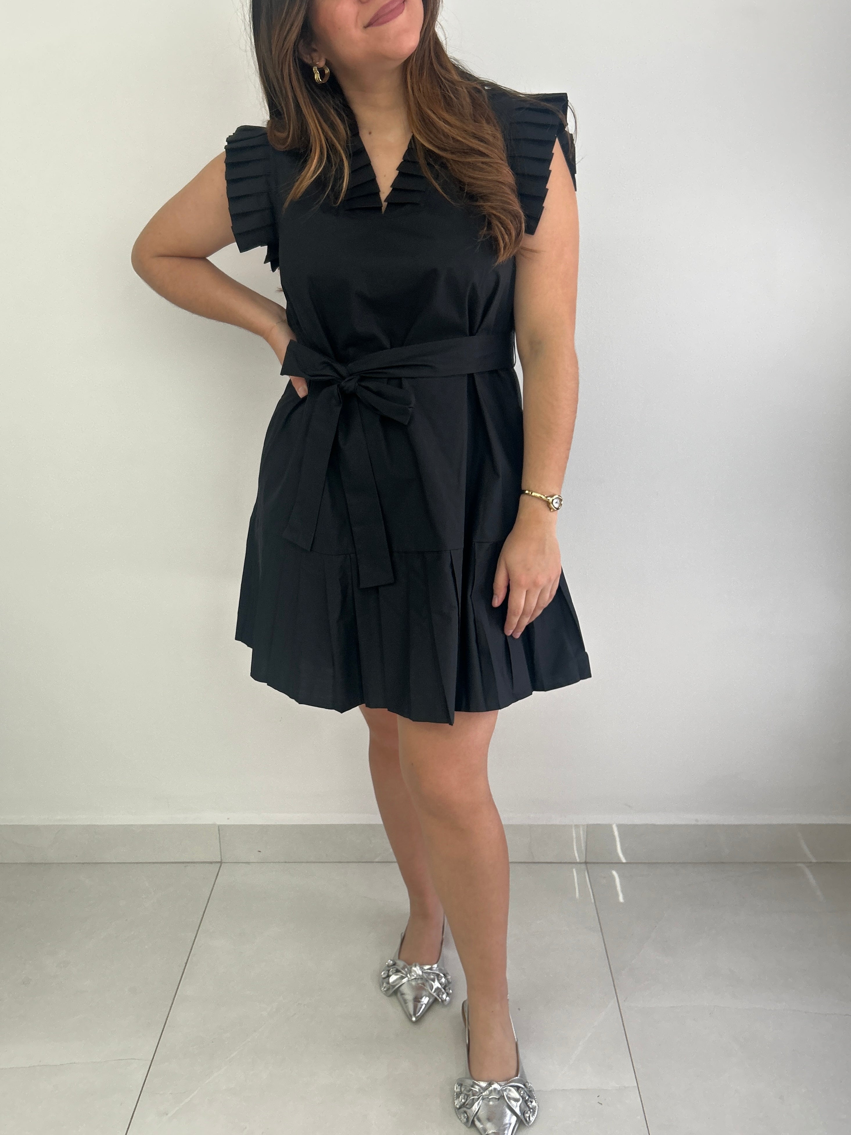 Woman wearing a black dress with ruffled sleeves against a white background