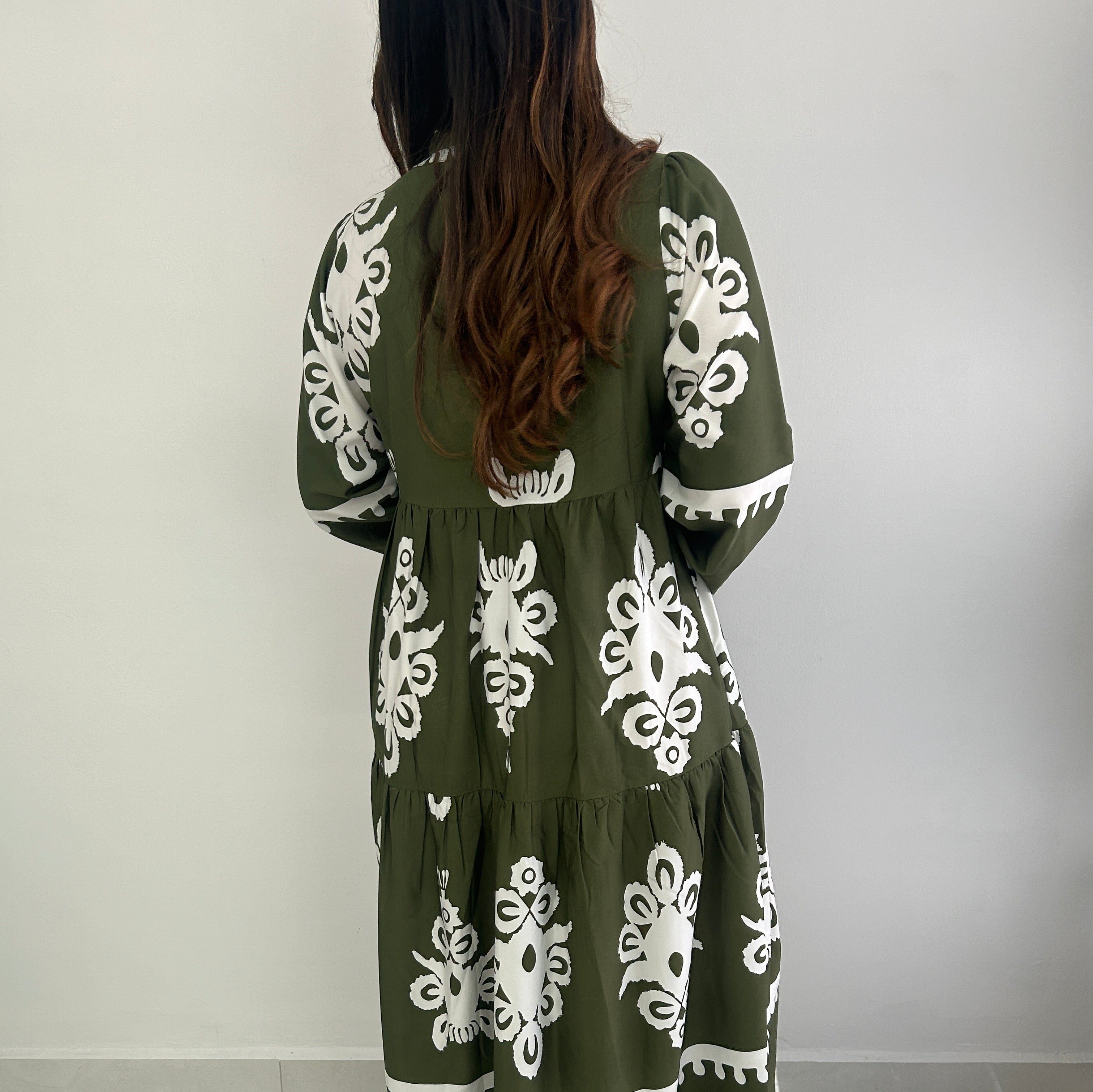 Person wearing a green dress with white floral patterns.