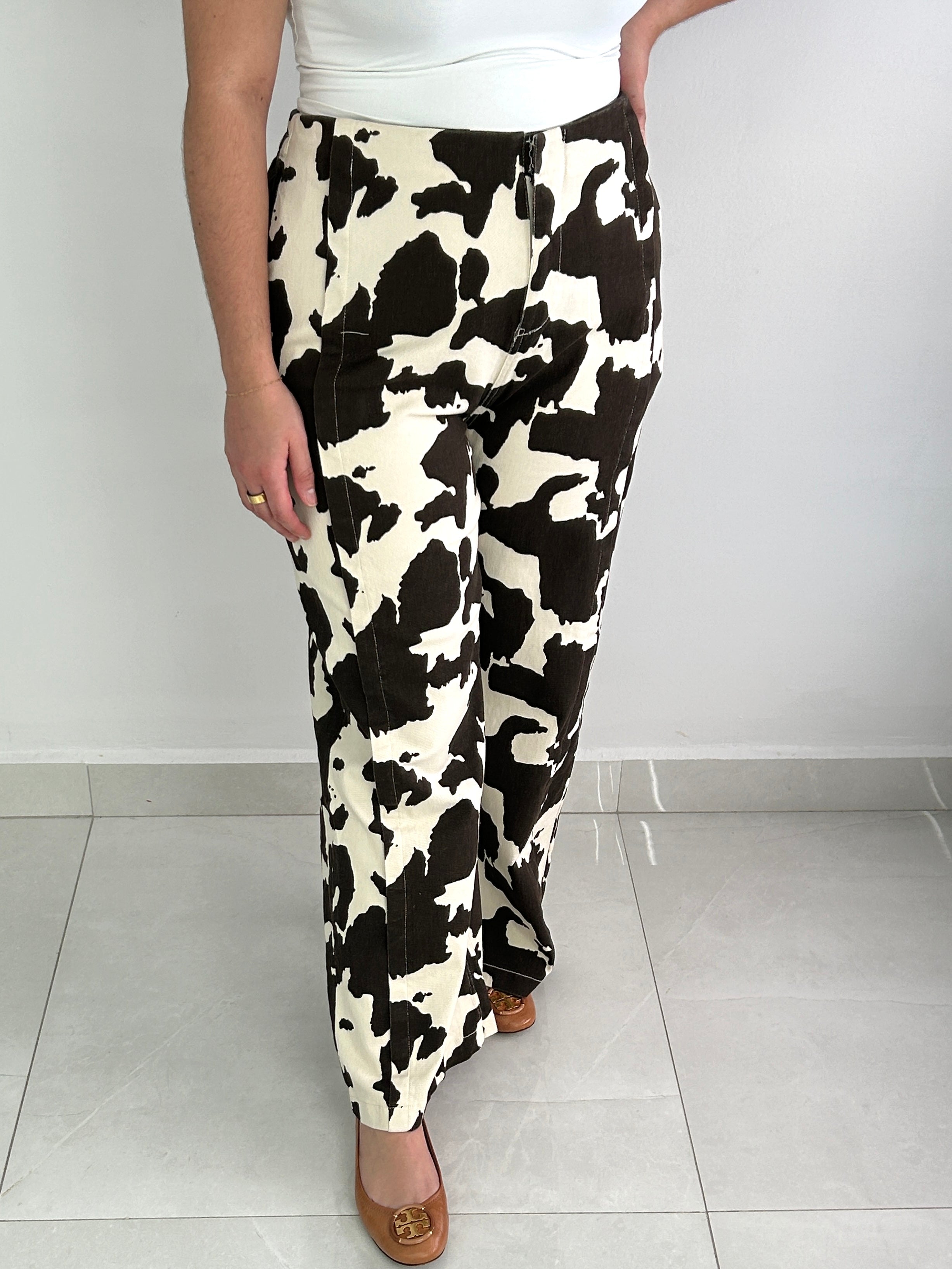 Person wearing a black and white cow print skirt on a plain background