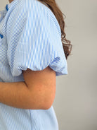 Person wearing a blue and white striped shirt with a plain background