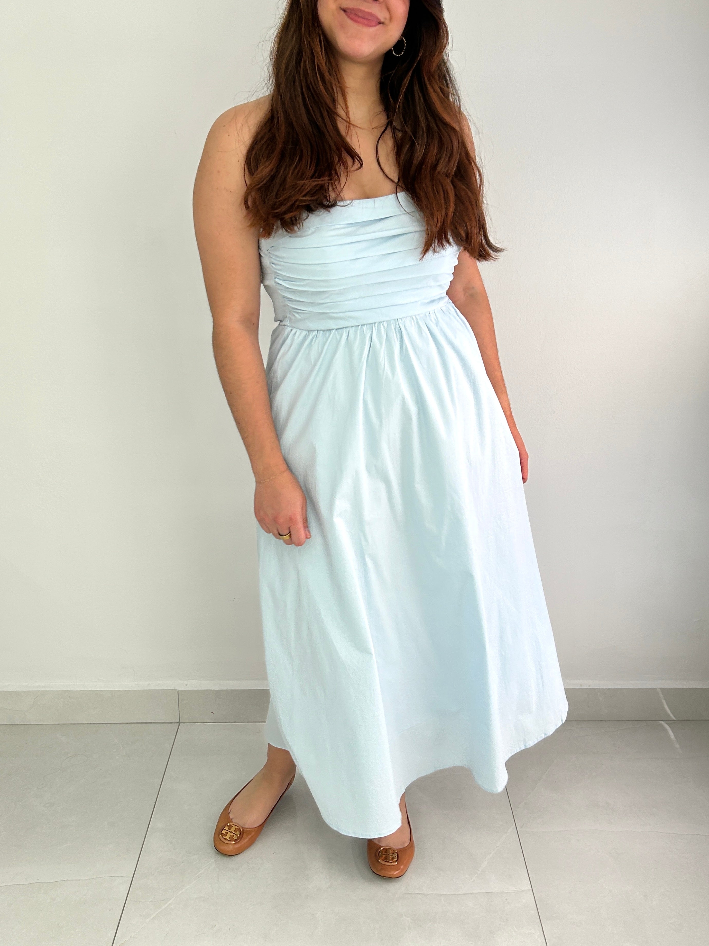 Woman wearing a light blue strapless dress against a plain background