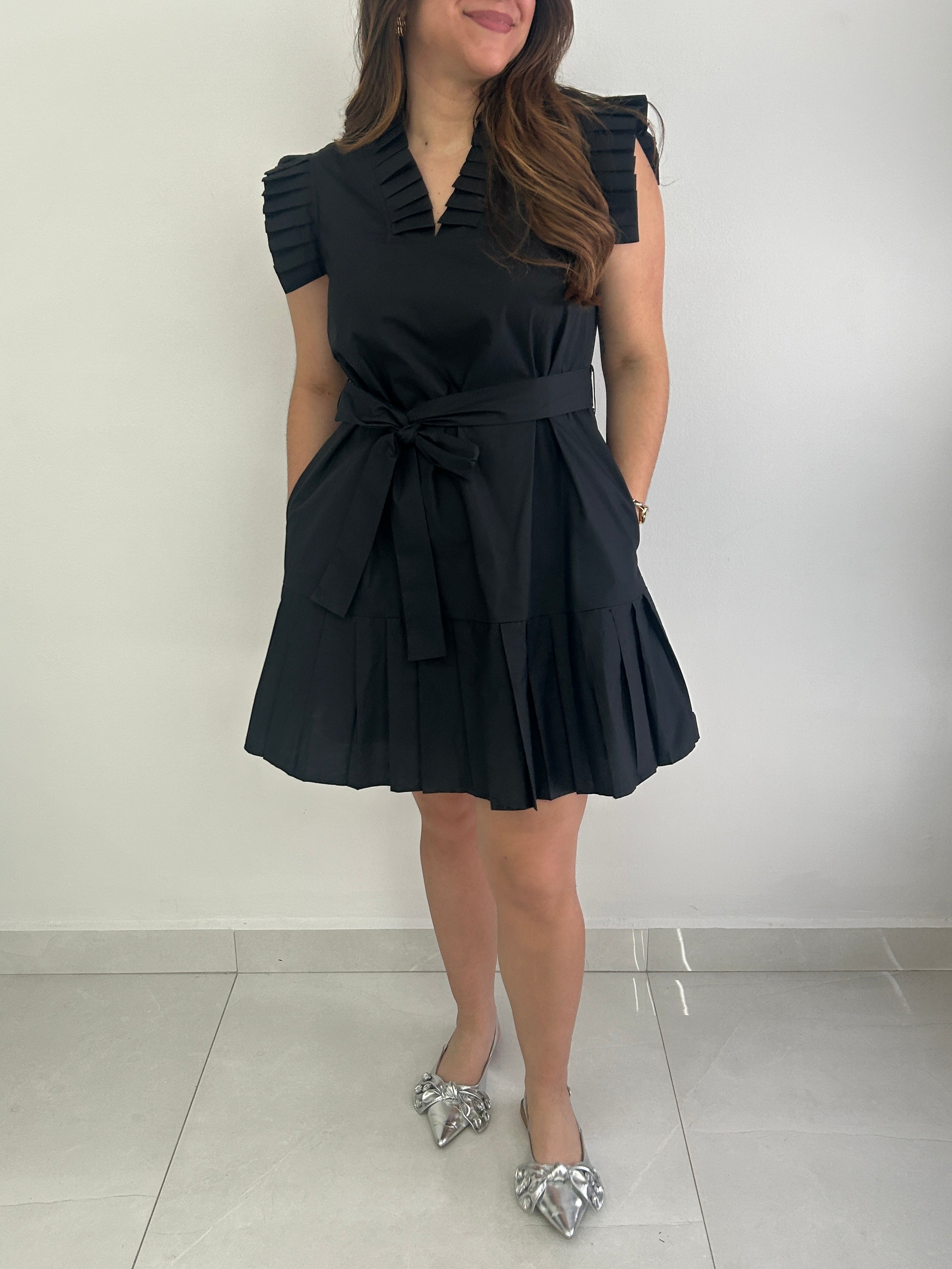 Woman wearing a black dress with a belt against a white background