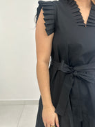Black pleated dress with a tie detail on a white background