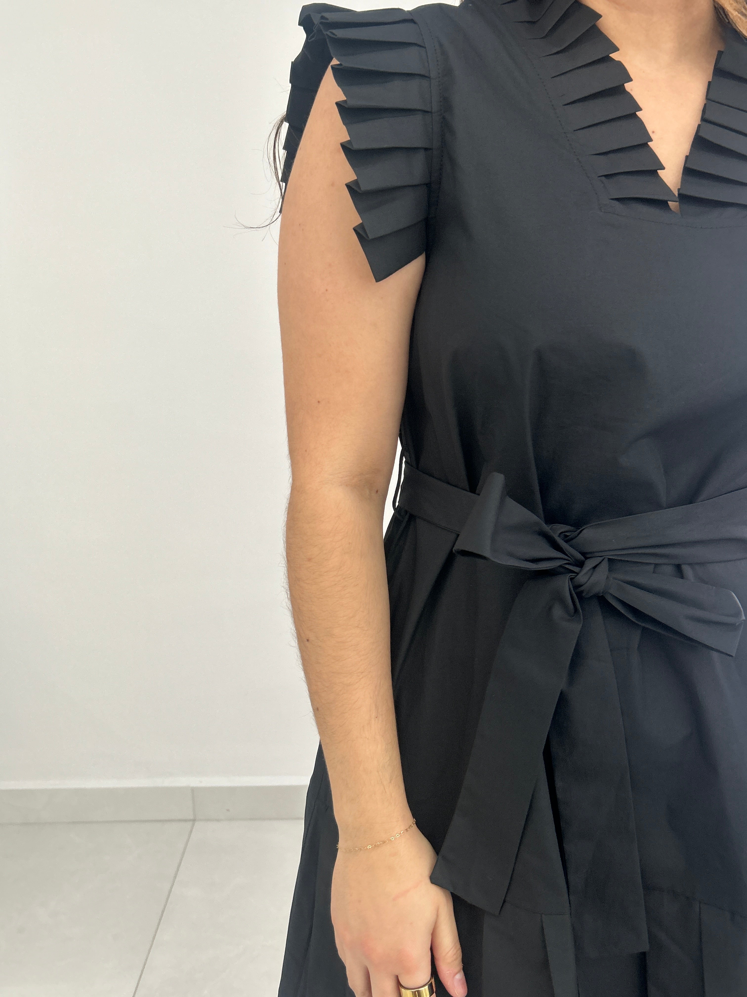 Black pleated dress with a tie detail on a white background