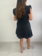 Person wearing a black dress with pleated details.
