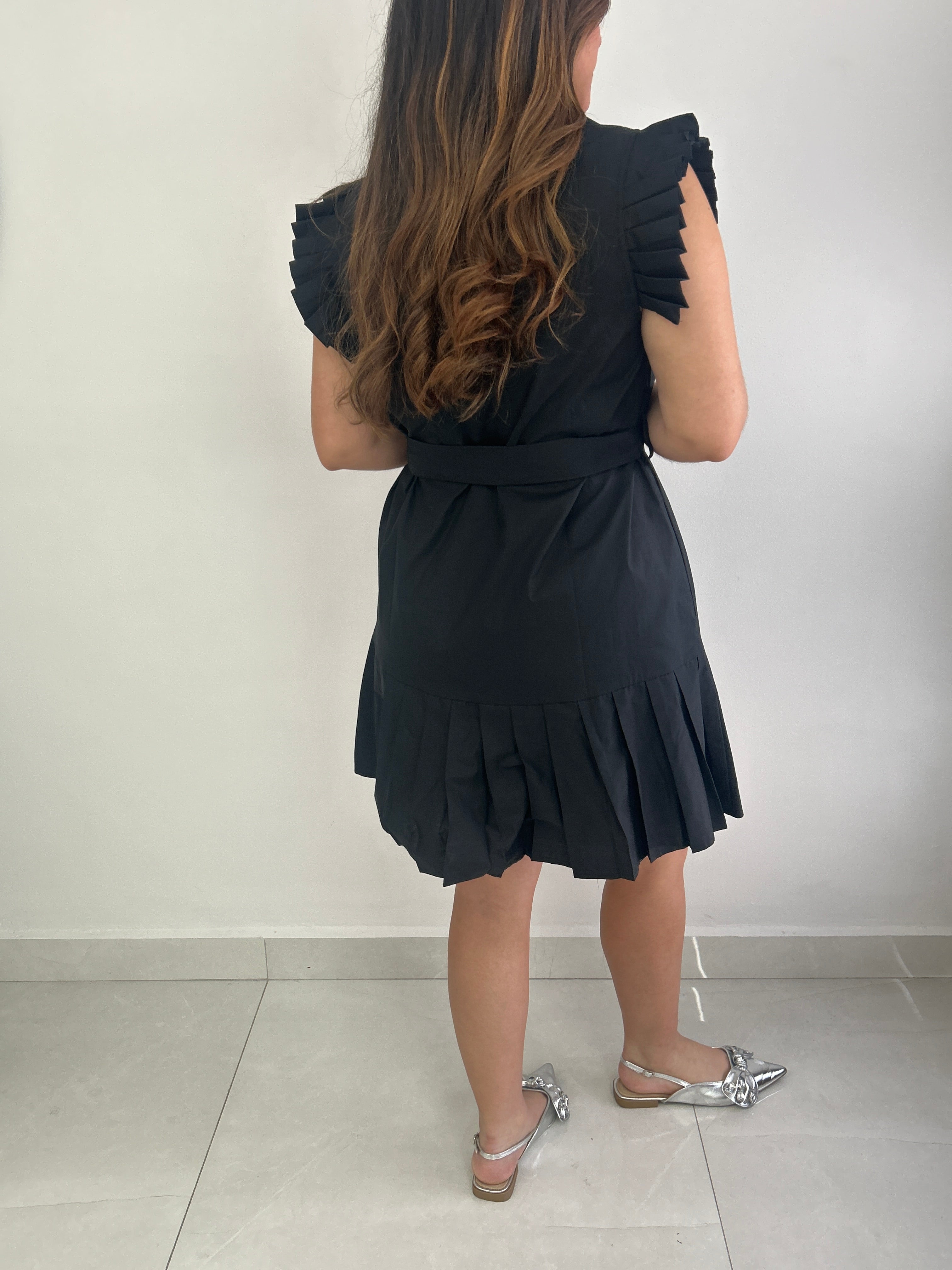 Person wearing a black dress with pleated details.