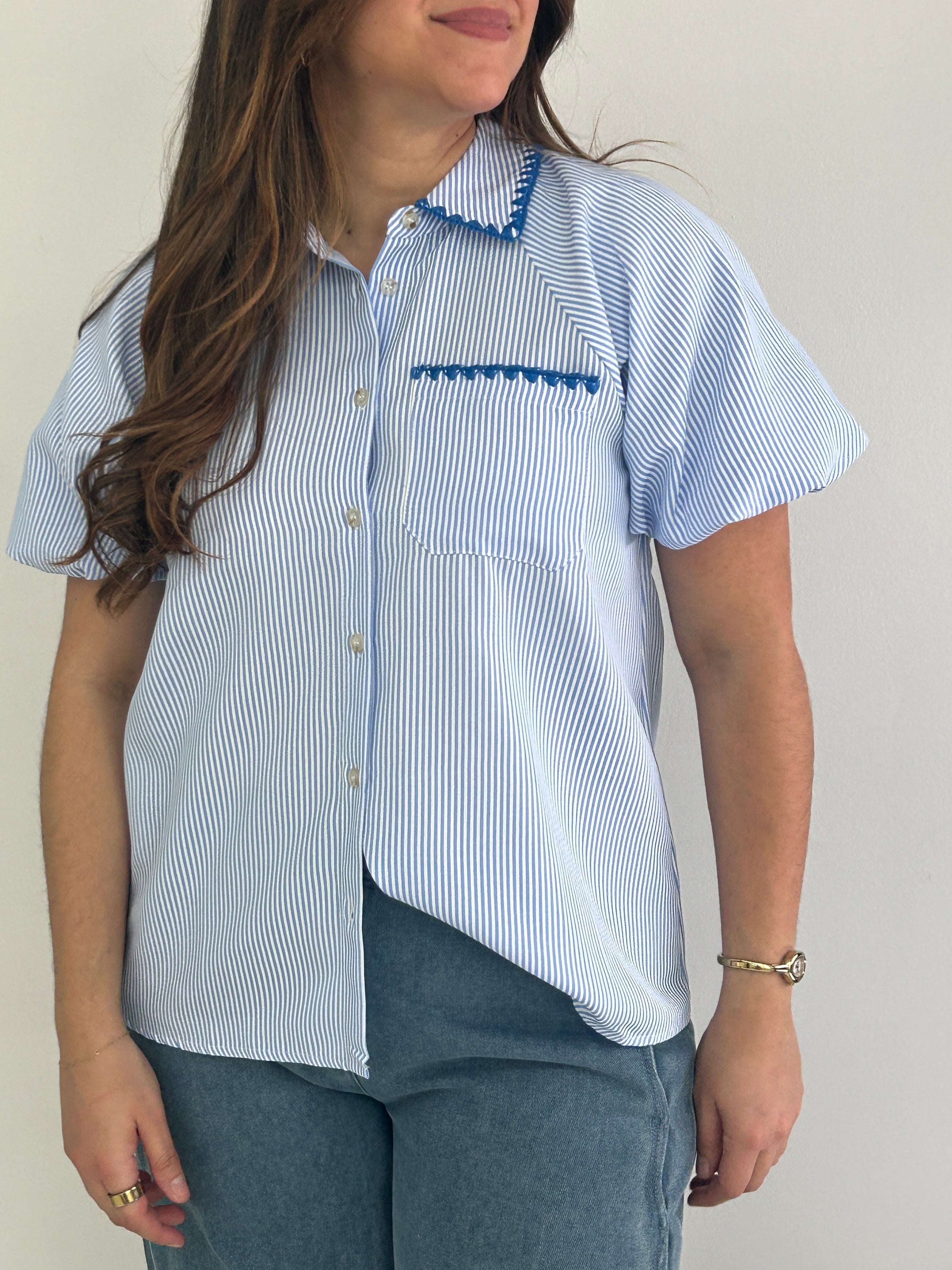 Person wearing a blue and white striped shirt with a plain background
